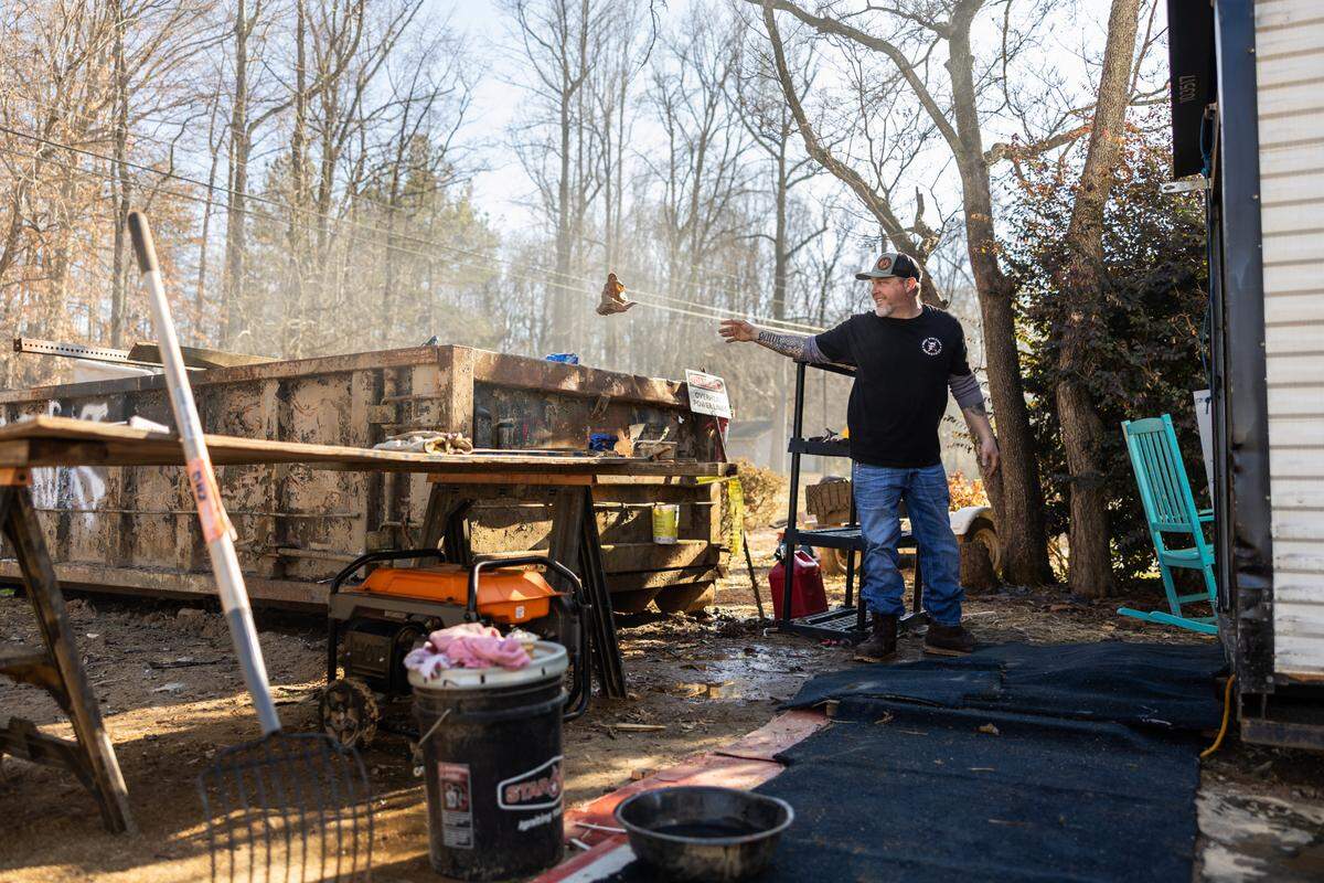 Donnie McGuire clears trash as he works on salvaging belongings from his flood-damaged home on Lake Drive in Charlotte earlier this month. “We still don’t really know what’s going on,” he says of where things stand with his insurance claim.