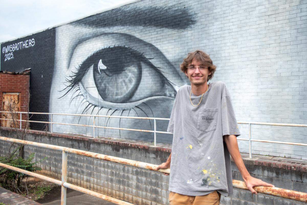 Albemarle native and muralist Eli Williams poses in front of his work on Pee Dee Avenue in Albemarle. Eli and his brother Jack returned to live in Albemarle after completing their respective art degrees and manage their business, WMSBrothers.