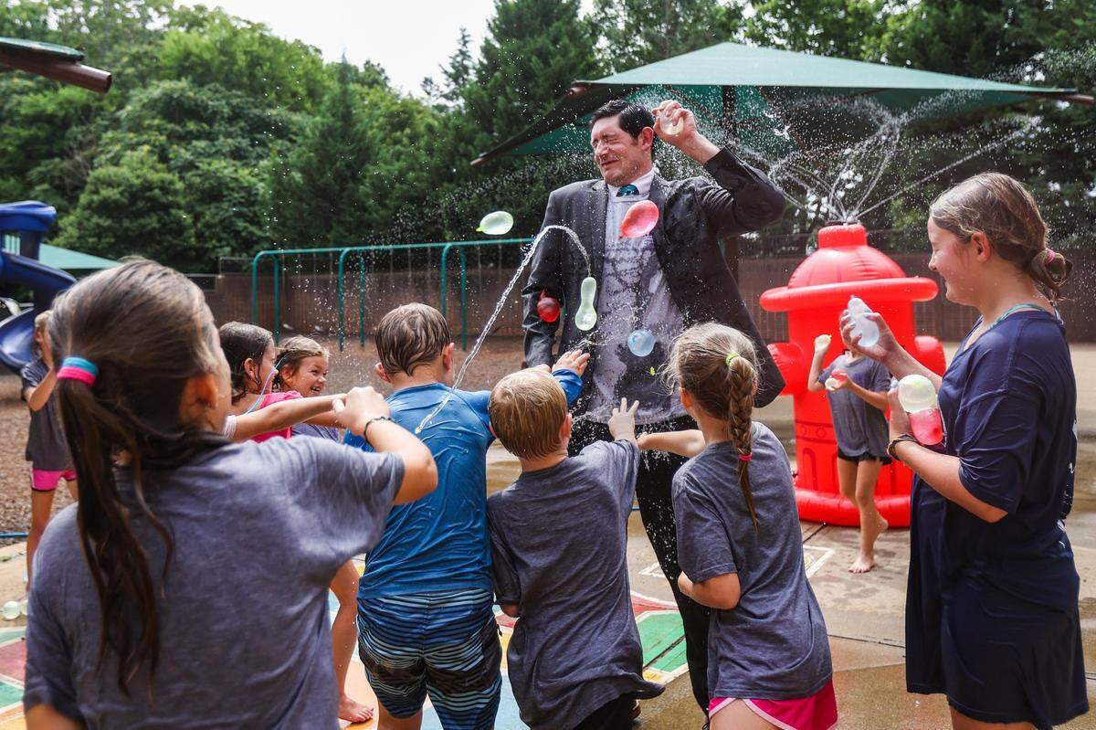 Kids collectively throw water balloons at the Superintendent for Catholic Schools for the Diocese of Charlotte, Dr. Gregory Monroe, during recess at summer camp at St. Matthew Catholic School in 2022.
