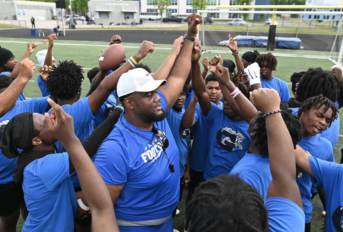 Garinger High School head football coach Jupiter Wilson, center, gathers his players together following a workout on Tuesday, April 29, 2025. Garinger High School has been through dozens of coaches trying to turn the program around. Now, the former UNC football player is taking his turn.