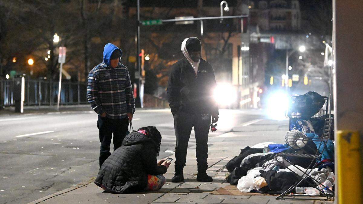 Point-in-Time Count volunteers Jeanelle Perry, sitting, Joe Hamby, left-standing, and Jerald Collins, right, speak with a person who is homeless along Church St. in uptown Charlotte, NC., on Thursday, January 26, 2023. Volunteers aim to get an accurate statistic of how many people in Charlotte are homeless, live in shelters or tents or cars, or otherwise have unstable housing arrangements.
