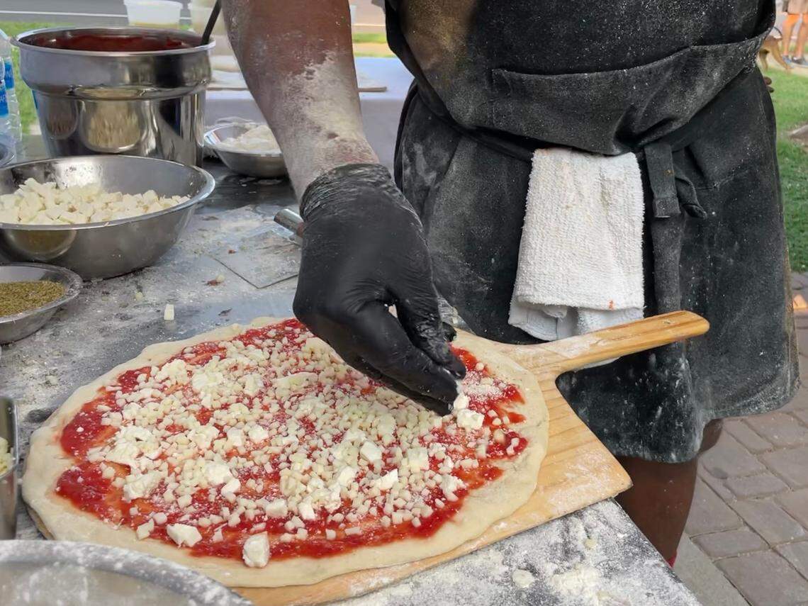 Kerrel Thompson scatters cheese on a pizza during a pop-up at Crafty Beer Guys in Huntersville on July 23, 2021.