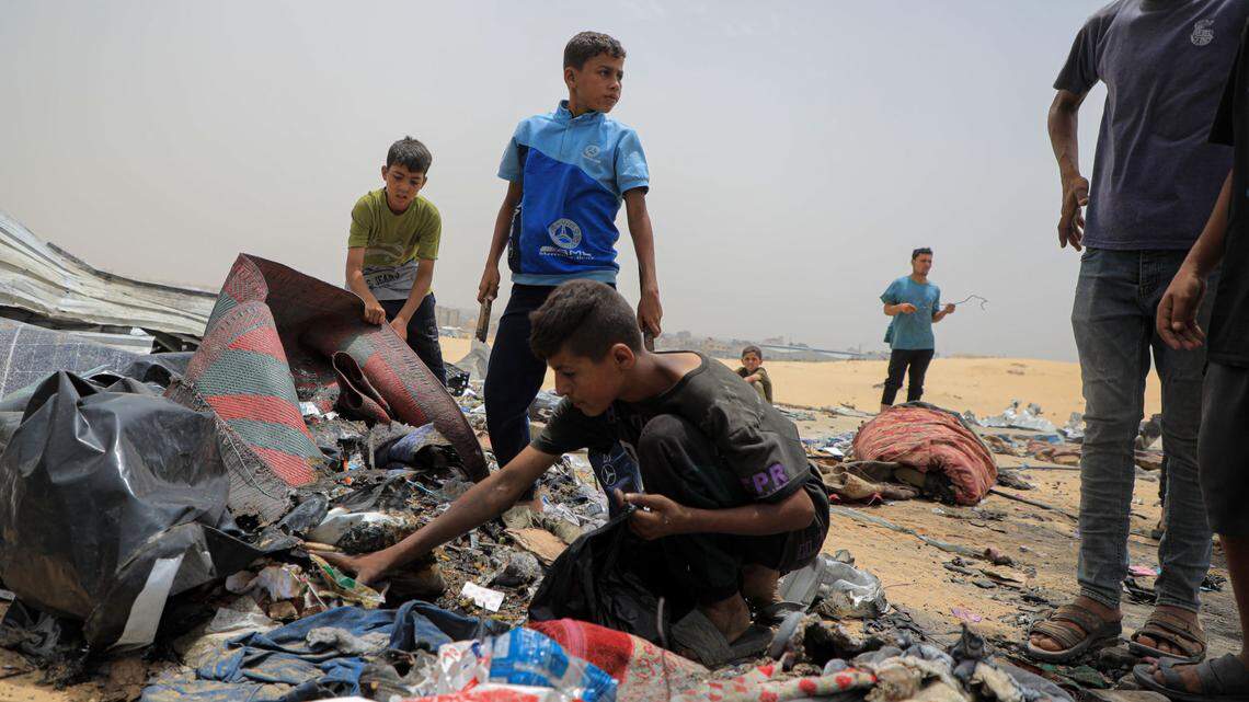 Palestinians collect items after an Israeli airstrike on tents for displaced people near the southern Gaza Strip city of Rafah on May 27, 2024. At least 45 Palestinians, including children, were killed.