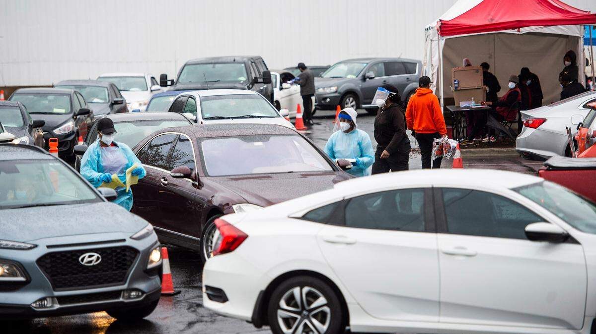 Healthcare workers tend to cars waiting in line for COVID tests at StarMed Healthcare on Tuckaseegee Road on Thursday, December 30, 2021 in Charlotte, NC.