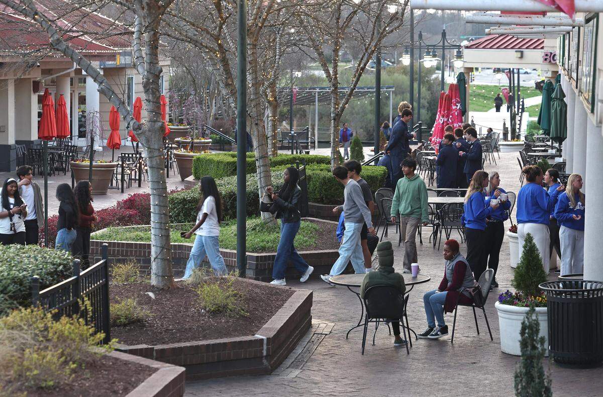 Friends congregate near businesses at The Boardwalk in the University City area on Friday, March 13, 2026. Despite its size, density and growth, The Boardwalk (formerly known as The Shoppes at University Place) University City area has not developed a good independent restaurant scene.