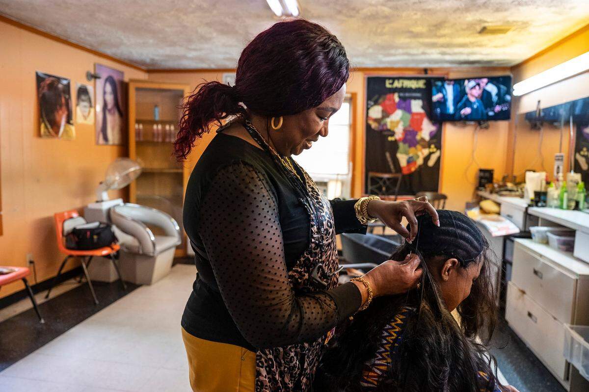 Moyhe-Eugenie N’Dri-Zie sews in hair on a customer at her business, Moyhe’s African Hair Braiding, on Central Avenue in Charlotte.