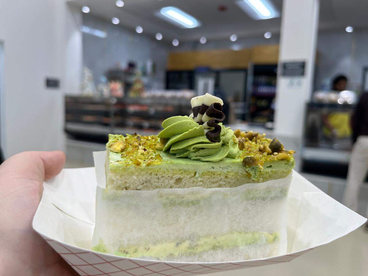 A slice of pistachio cake from the bakery case at Triveni Supermarket.