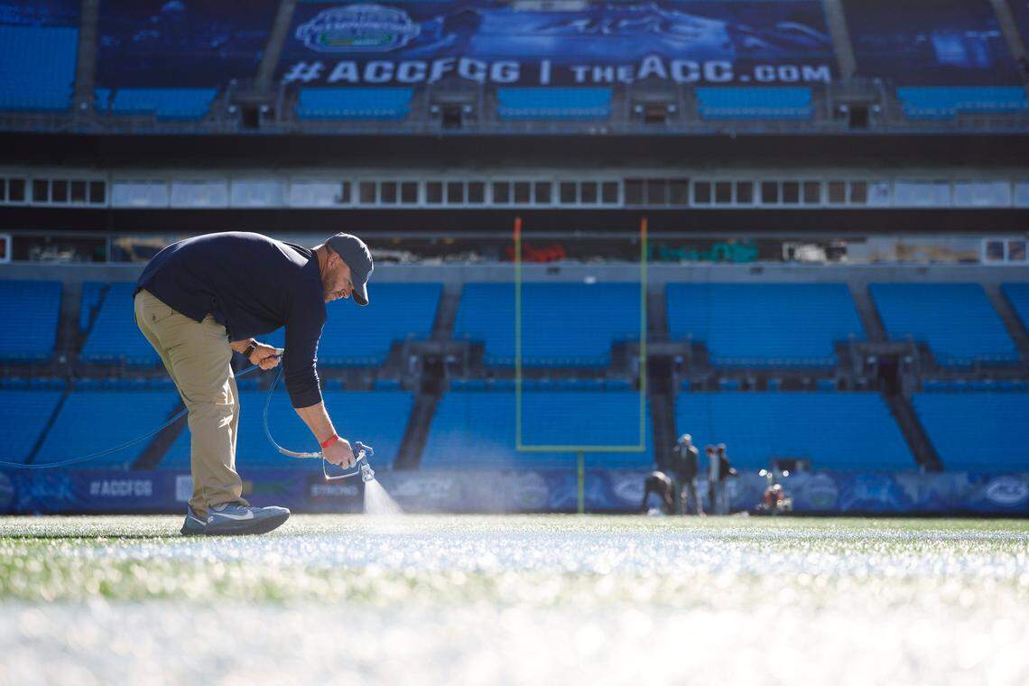 Casey Carrick, of Raleigh, N.C., a member of the UNC grounds crew works to paint the field for the ACC Championship football game against Clemson at Bank of America Stadium in Charlotte, N.C., Thursday, Dec. 1, 2022.