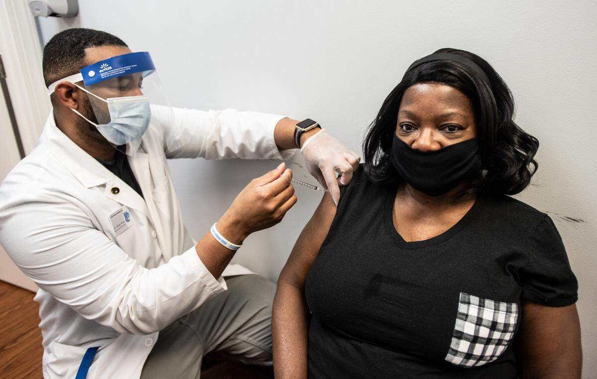 Venus Caselberry (right) is administered the COVID-19 vaccine by Dr. Martez Prince at Premier Pharmacy And Wellness Center in Charlotte, NC, on Thursday, March 18, 2021.