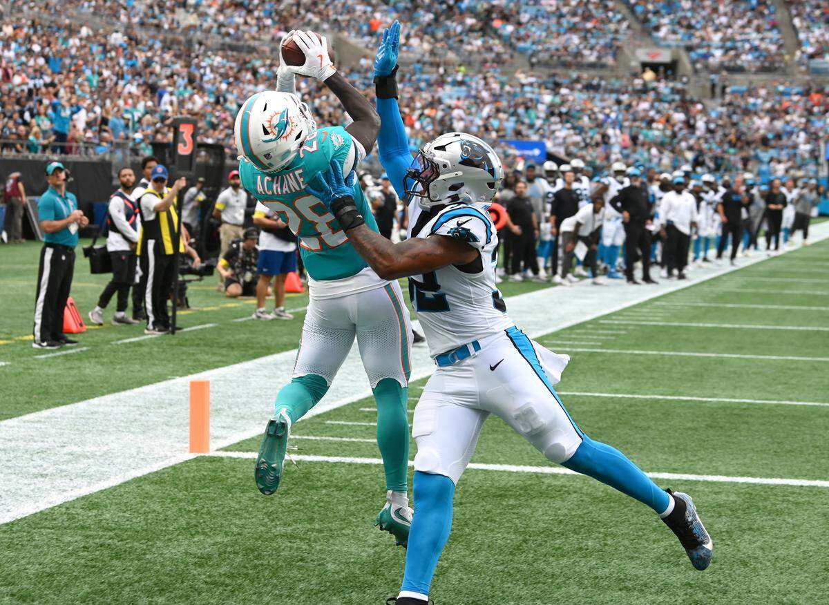 Miami Dolphins running back De'Von Achane, left, leaps to catch a pass in the end zone as Carolina Panthers linebacker Trevin Wallace, right, applies pressure during action on Sunday, Oct. 5, 2025 at Bank of America Stadium in Charlotte, North Carolina.