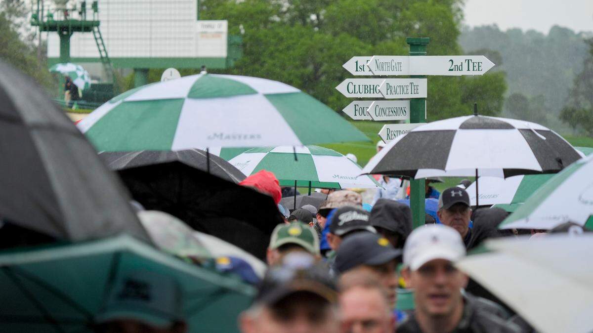 Patrons leave the course as inclement weather suspends play Monday during a practice round of the Masters Tournament at Augusta National Golf Club.