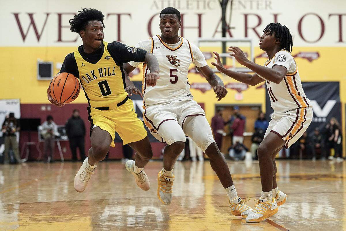 Oak Hill Academy's Kam Lawson (0) drives to the basket against West Charlotte's Jkhai Wade (5) and Major Cross (11) during the first half of a boys varsity basketball game, Friday, Dec. 19, 2025, in Charlotte, N.C.
