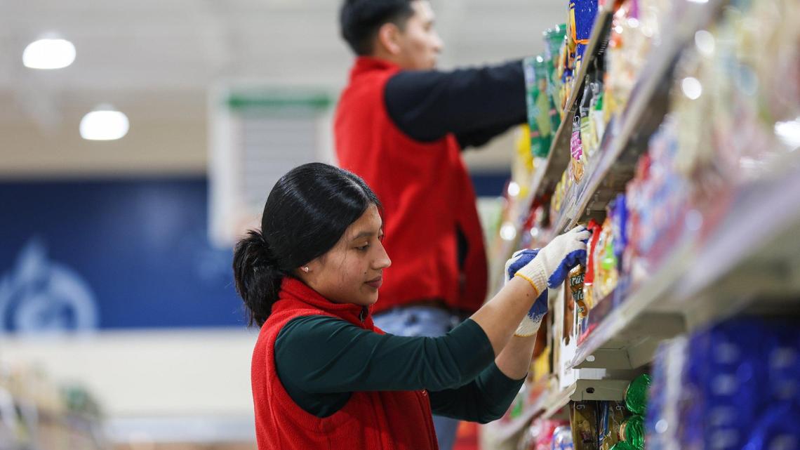 Employees help stock the shelves at the new Super G Mart in Pineville on Tuesday. The international supermarket, the third location for the brand, is slated to open this weekend.