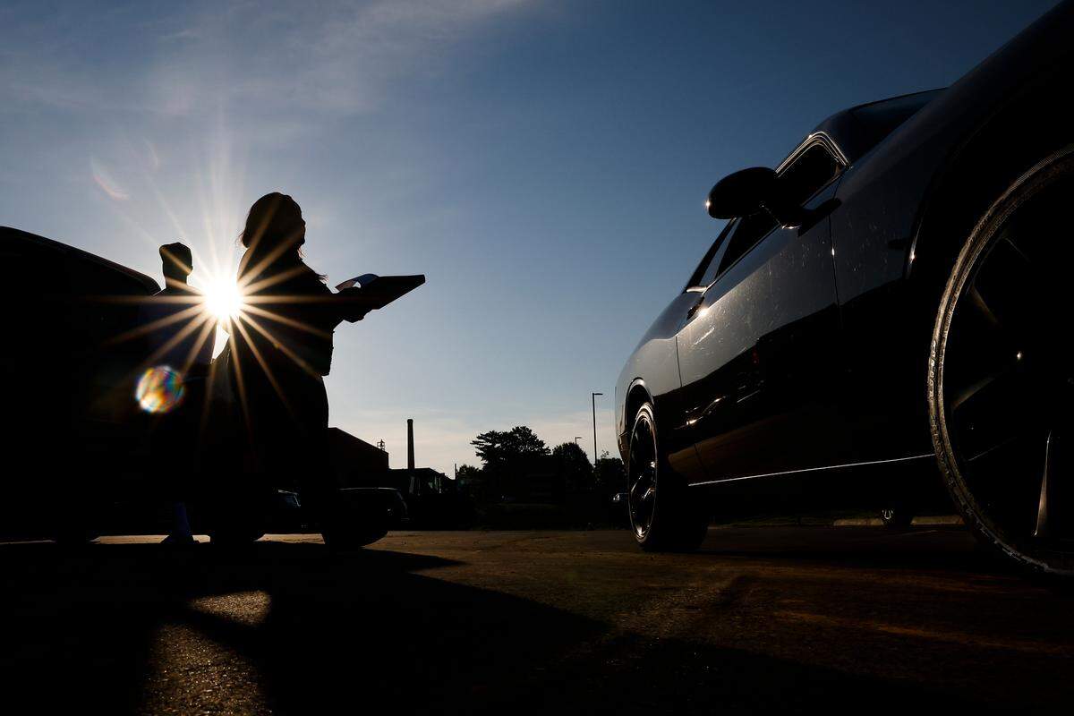 Lakeisha Barringer, mother of West Charlotte student and football player Caleb Barringer, goes car to car asking other parents to sign a petition to reinstate coach Sam Greiner on Thursday, Aug. 4, 2022.
