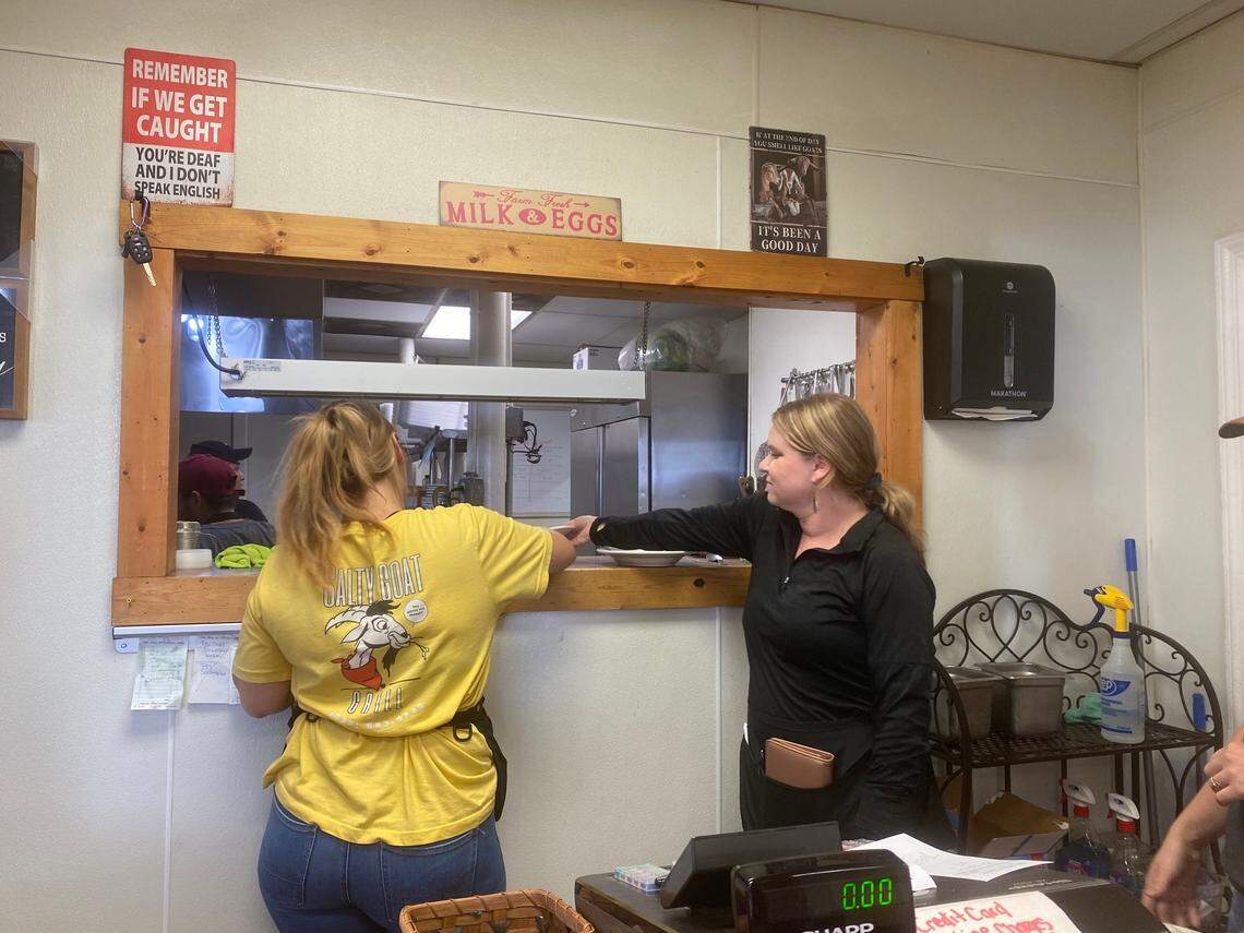 Waitresses including Dani Walker, right, wait for orders from the kitchen at Salty Goat Grill, where Western North Carolina residents have gathered in the aftermath of Hurricane Helene.