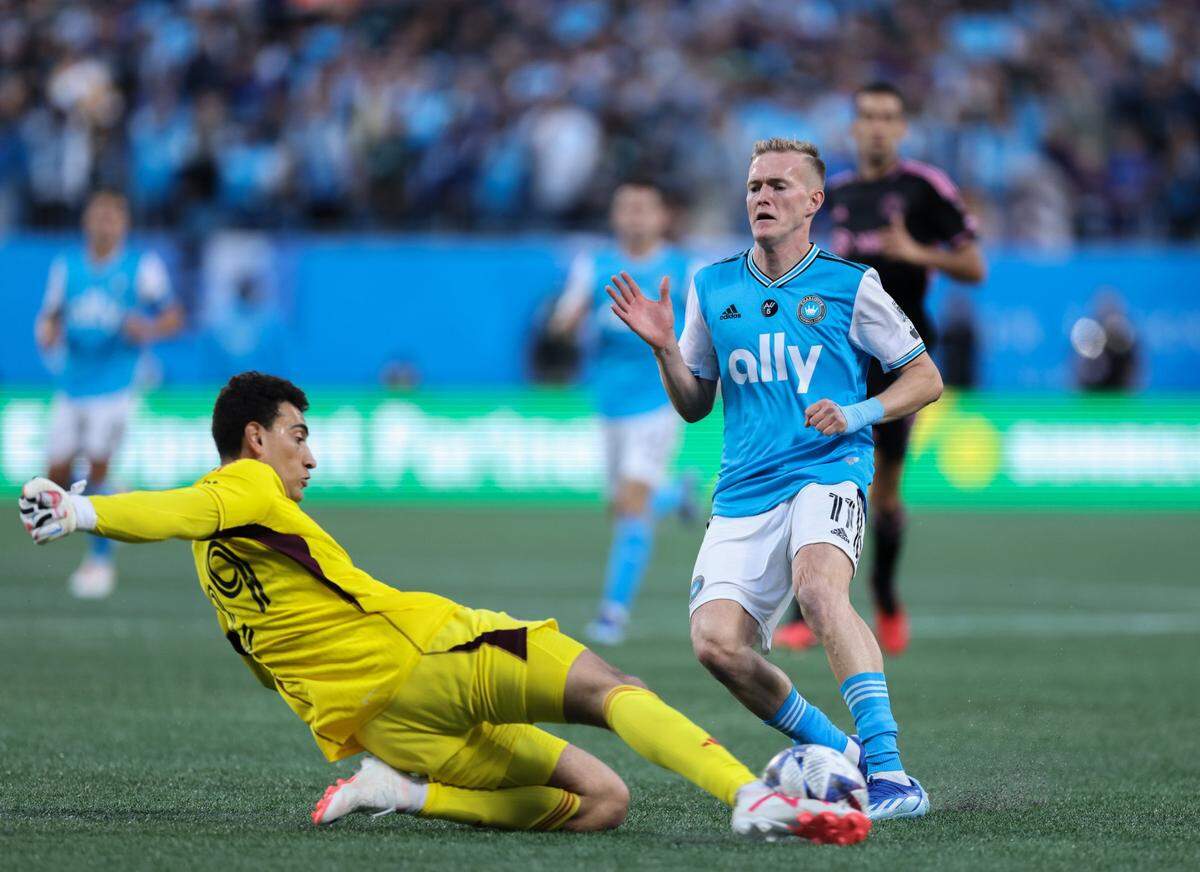 Inter Miami goalkeeper CJ dos Santos, left, slide-tackles in front of Charlotte FC forward Karol Swiderski at the Bank of America Stadium in Charlotte, N.C., on Saturday, October 21, 2023.