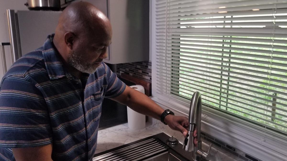 A Charlotte landlord checks a faucet at a home property where single rooms are rented to tenants.