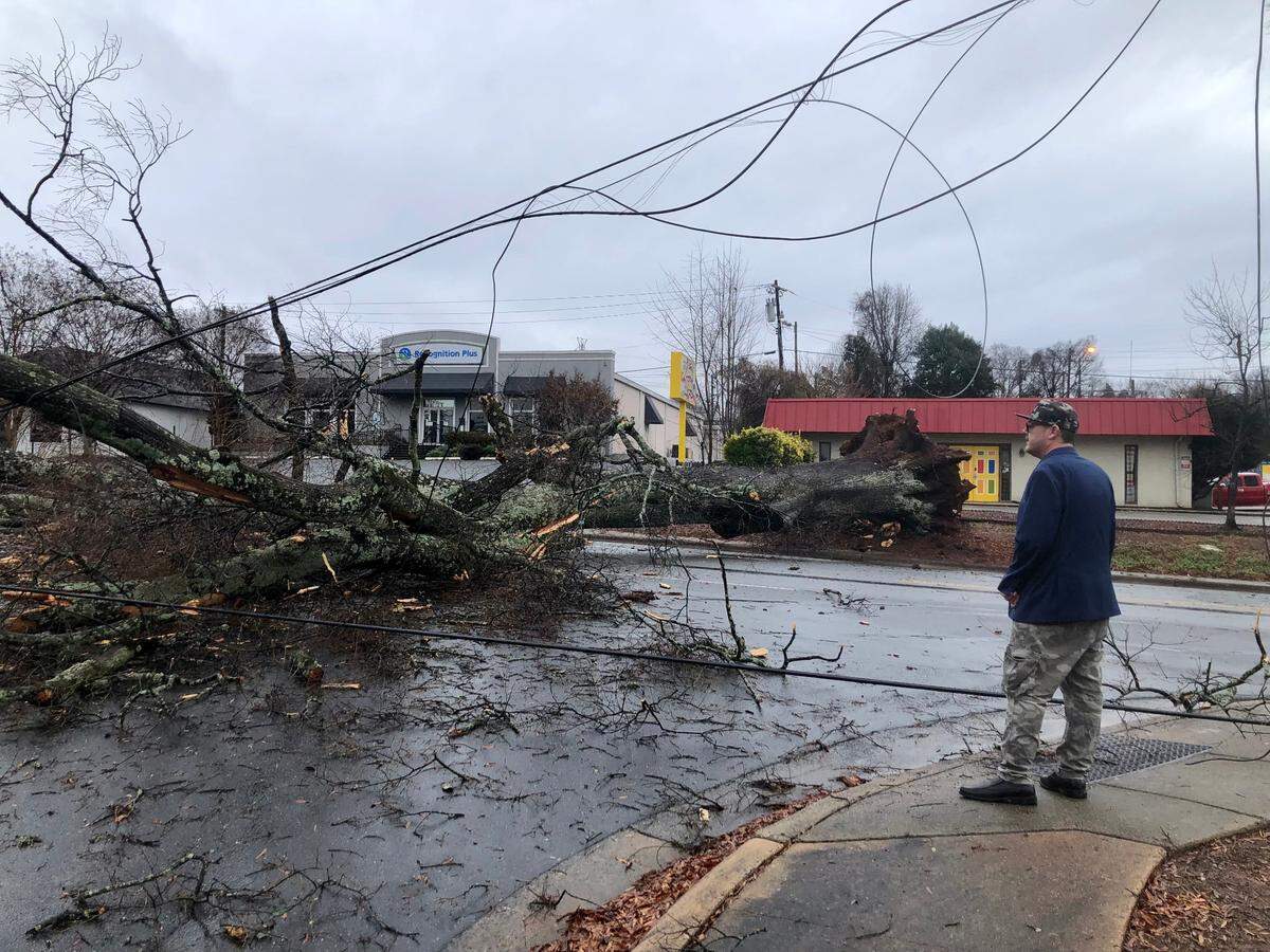 Charlotte resident Anthony Henning looks at a fallen tree across Monroe Road and Colonnade Drive in Charlotte, NC on Sunday morning Dec. 29, 2024 following a heavy rain and wind storm that swept through the area.