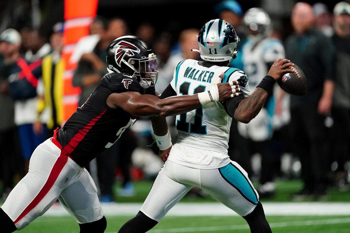 Carolina Panthers quarterback PJ Walker (11) throws under pressure from Atlanta Falcons linebacker Lorenzo Carter, left, during the second half of an NFL football game Sunday, Oct. 30, 2022, in Atlanta.