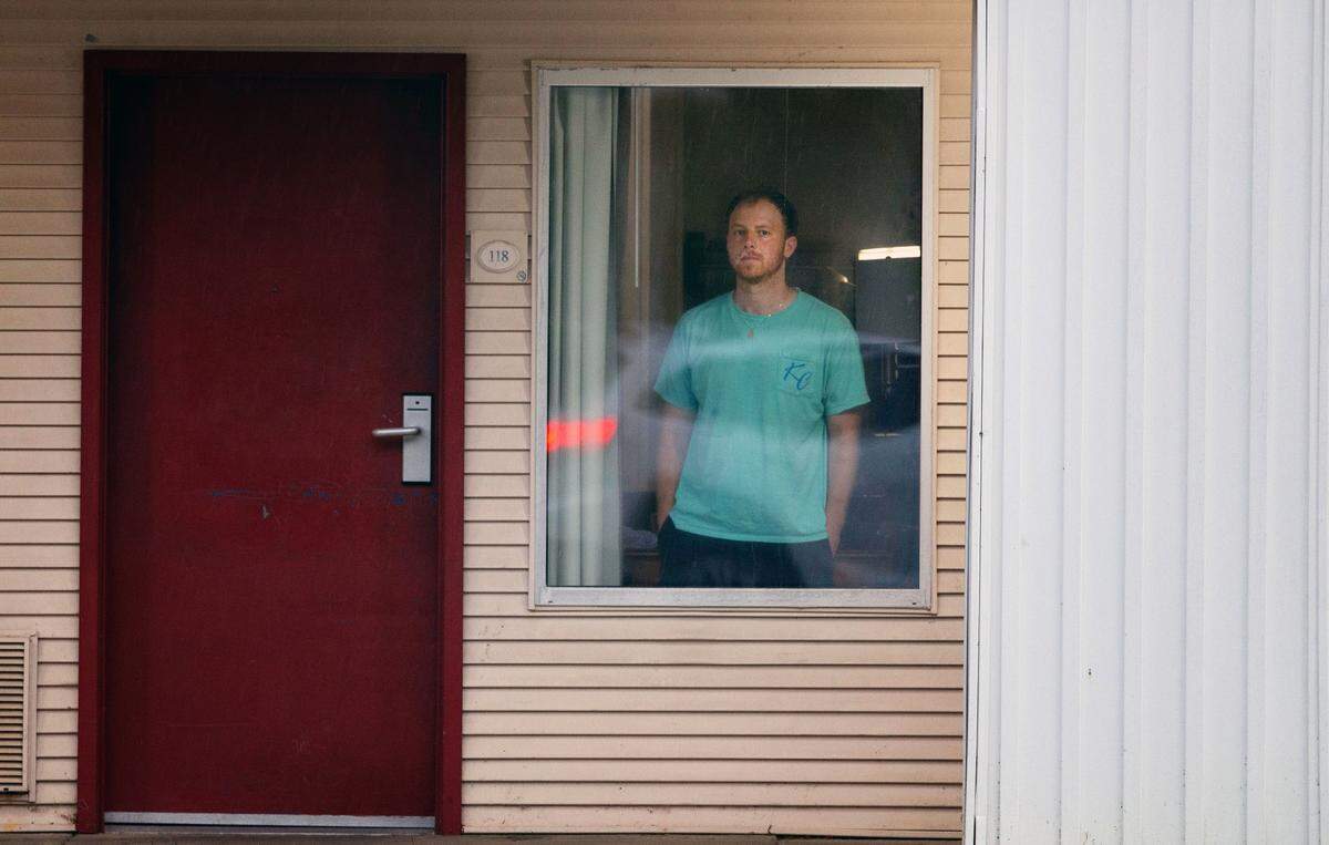 Aaron Hall, 32-year-old from Kansas City, stands in the window of the Econo Lodge near the Charlotte Douglas Airport, where he stayed 10 days and nine nights in August after testing positive for COVID-19.Hall traveled to Charlotte from Chicago looking for a used Volvo 240 before getting sick from the coronavirus.