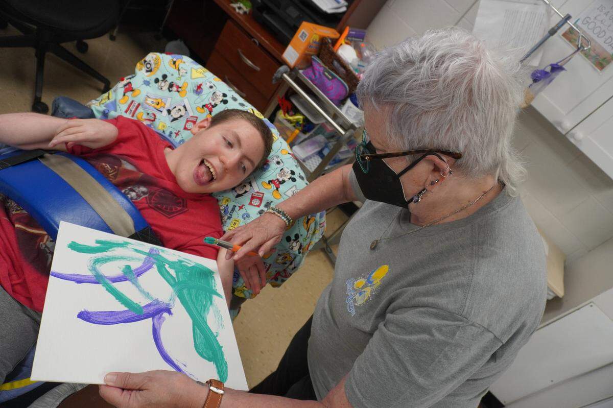 Gaye Dimmick, director of Bliss Gallery, works with artist Landon using a hand-over-hand technique. The gallery’s “Here & Where” exhibit is on display through Aug. 20.