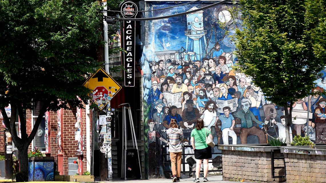 Passersby stop to take a photo of a mural along north Davidson. her fees or needing a permit, on street vendors NoDa. Some brick and mortar business owners offered their thoughts on the issue on Tuesday, June 10, 2025.