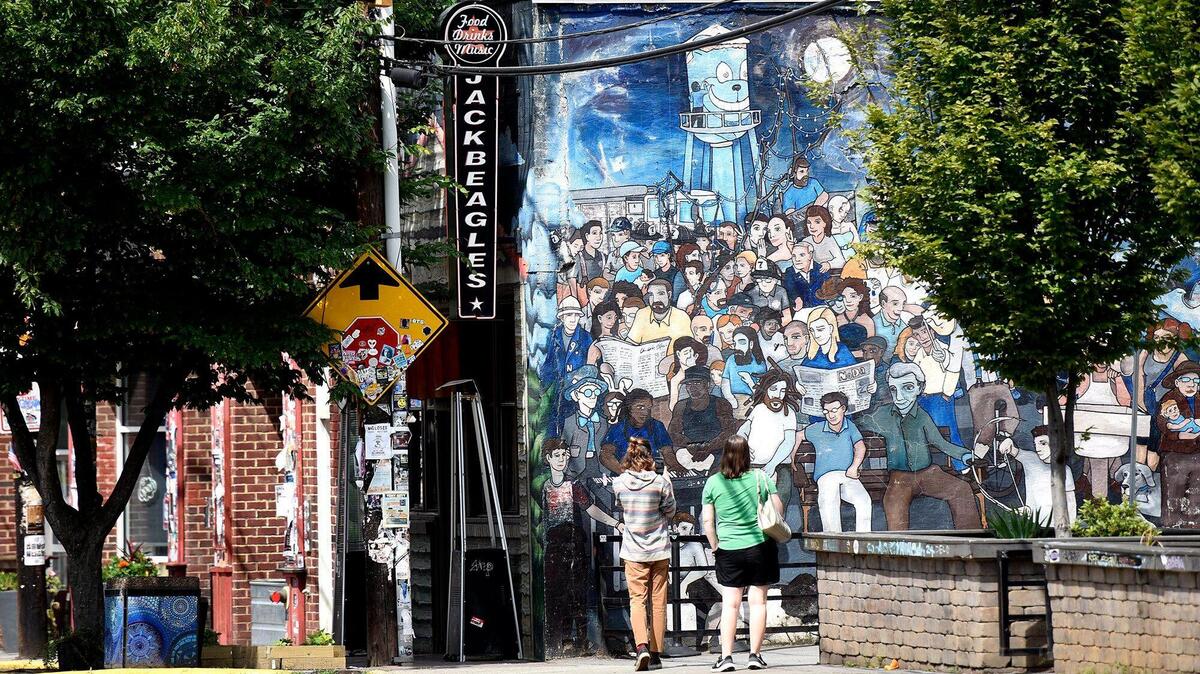 Passersby stop to take a photo of a mural along north Davidson. her fees or needing a permit, on street vendors NoDa. Some brick and mortar business owners offered their thoughts on the issue on Tuesday, June 10, 2025.