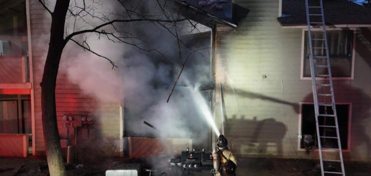 A firefighter shoots water at a fire in a Charlotte apartment building on Wednesday. A person who was found dead after the fire died before flames broke out, fire officials said.