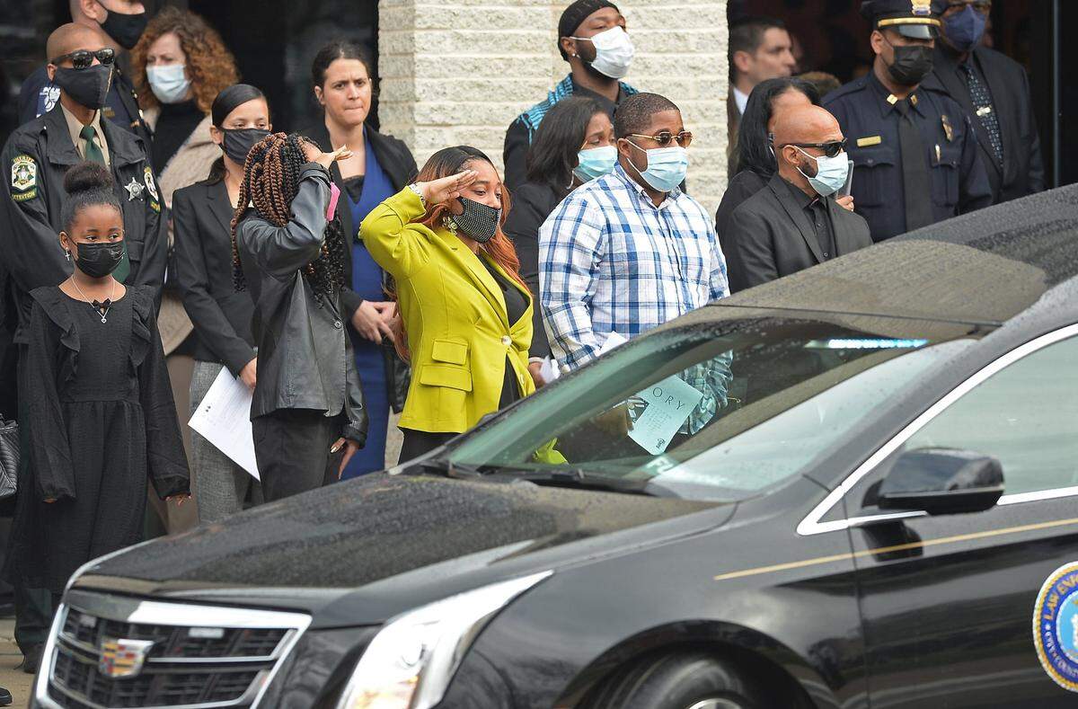 Two mourners salute CMPD Officer Mia Goodwin as the hearse leaves First Baptist Church in Charlotte, NC on Wednesday, December 29, 2021. Officer Goodwin was killed while responding to a crash on Interstate 85 on December 22, 2021.