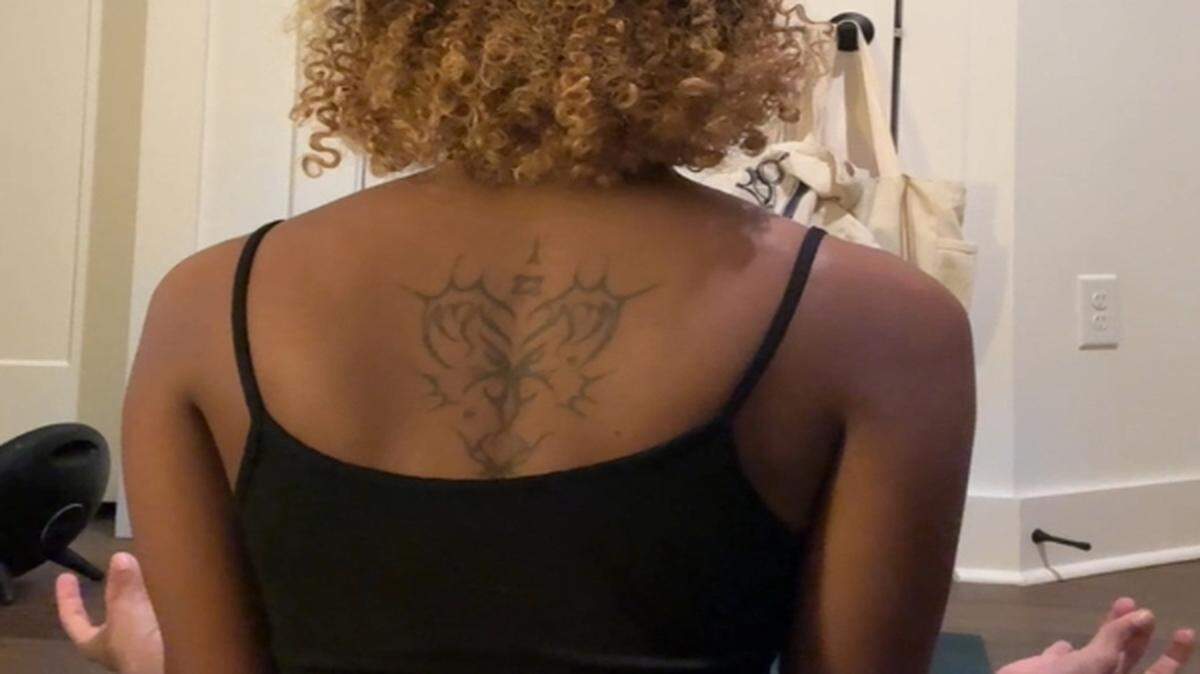 Amber Owens shows off her back tattoo, while seated in her apartment in Charlotte. After a lot of research, Owens found a Black woman artist to do her tattoo.