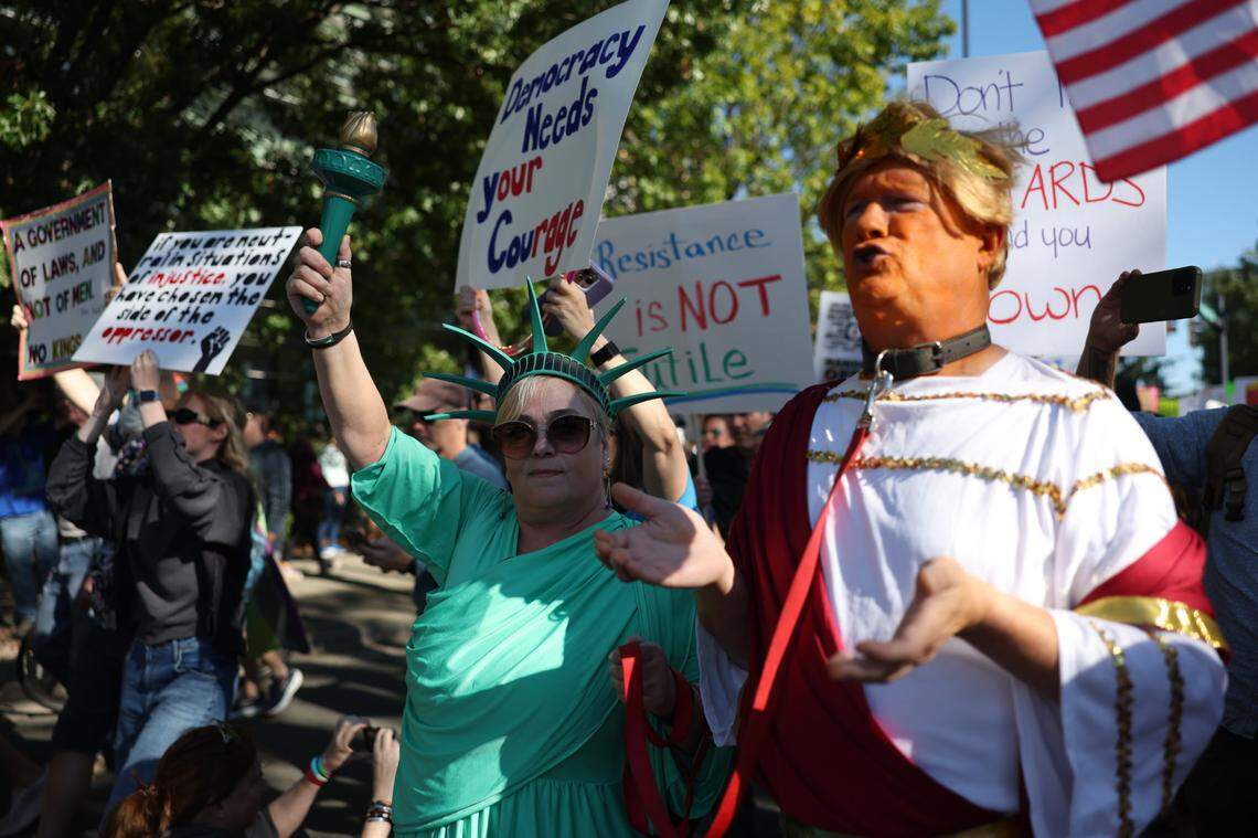 A woman in a Statue of Liberty costume and a Donald Trump impersonator participate in the ‘No Kings’ rally in uptown Charlotte on Saturday, Oct. 18.