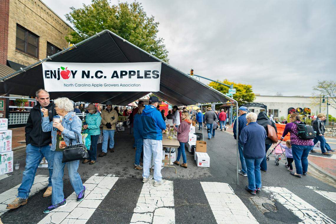 People enjoying the outdoor apple harvest festival.