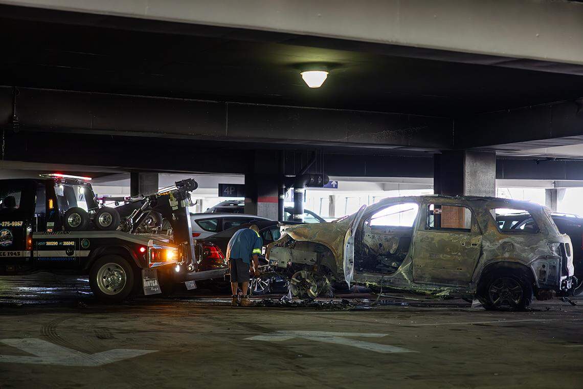 A damaged vehicle is being towed away from Charlotte Douglas International Airport parking deck Saturday morning, Aug. 10, 2024 were three people were injured in a two alarm fire.