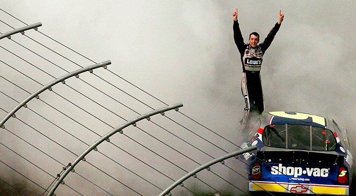 5/29/04 With smoke lingering in the air following his burnout, Kyle Busch raises his arms in celebration of his victory in the CARQUEST Auto Parts 300 Saturday at Lowe's Motor Speedway.  JEFF SINER/STAFF