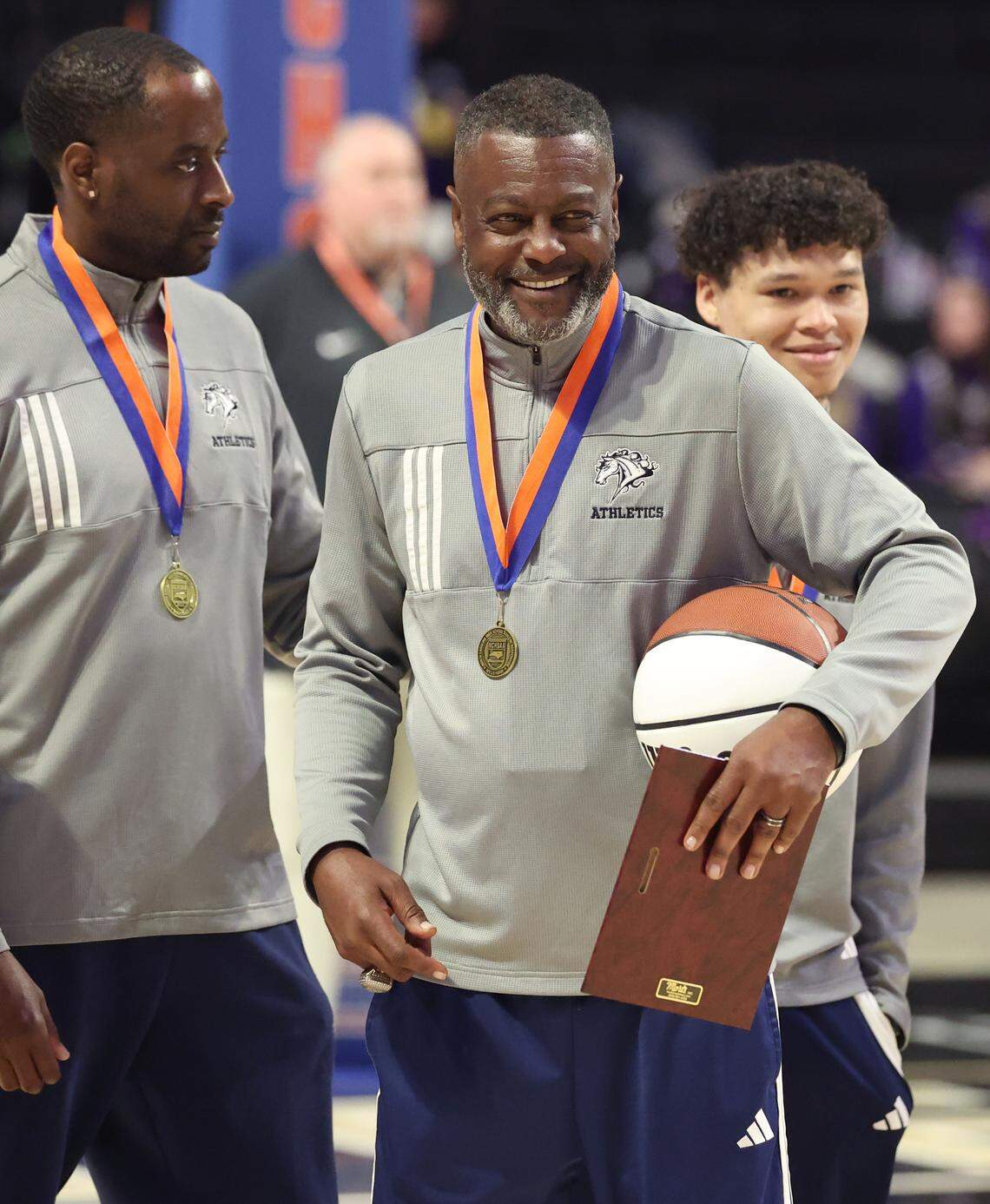 Queen’s Grant head boys’ basketball coach Joe Badgett smiles as his team receives their medals following their 77-43 win over Warren County in the NCHSAA 2A boys’ championship game at Lawrence Joel Veterans Coliseum in Winston-Salem, NC on Thursday, March 12, 2026.
