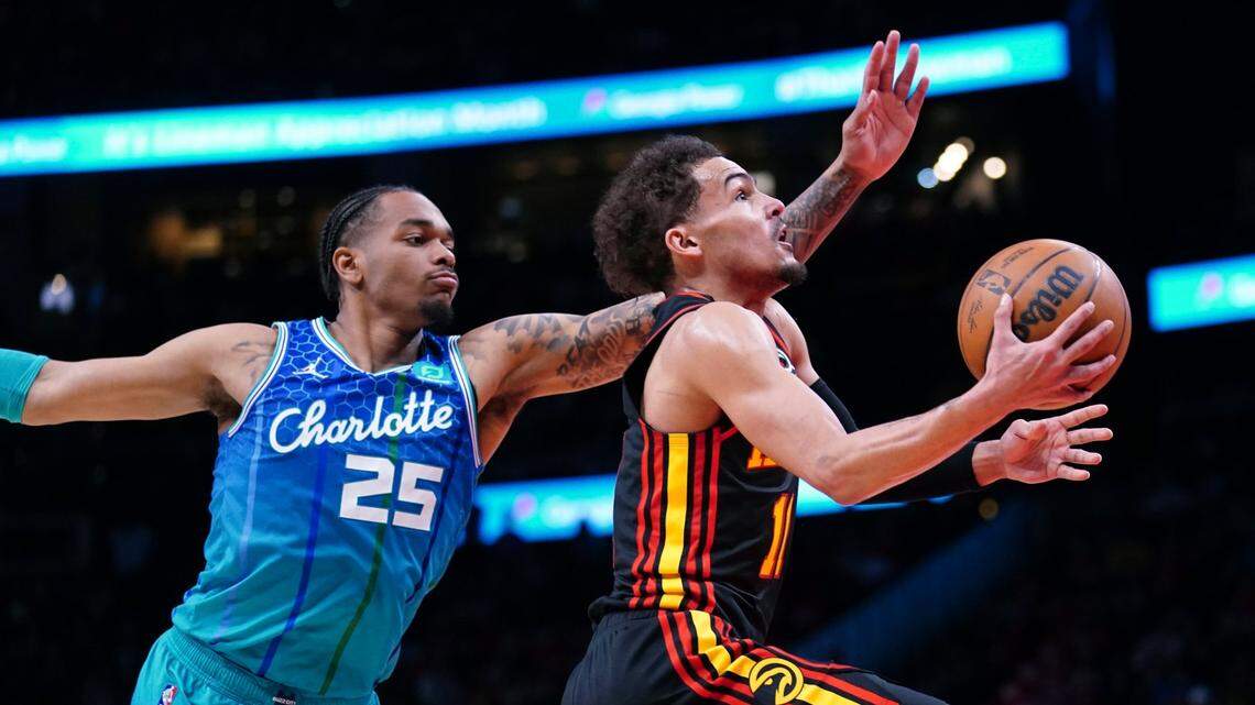 Atlanta Hawks guard Trae Young (11) drives to the basket past Charlotte Hornets forward P.J. Washington (25) during the first half of an NBA play-in basketball game Wednesday, April 13, 2022, in Atlanta. (AP Photo/John Bazemore)