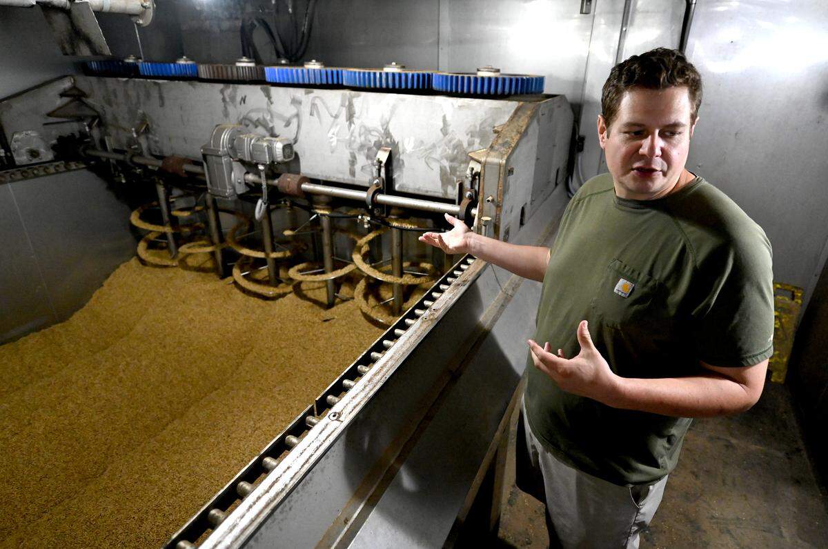 Carolina Malt House co-owner Aaron Goss stands along one of the two production lines where grains are dried after having been cleaned on Tuesday, April 23, 2025. Goss designed the machines.