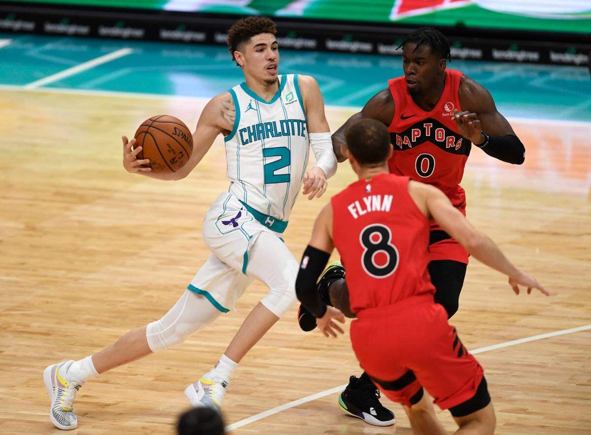 Charlotte Hornets guard LaMelo Ball (2) drives in on Toronto Raptors guard Malachi Flynn (8) and guard Terence Davis II (0) in the second half of an NBA preseason game at the Spectrum Center on Monday. The Raptors won, 112-109, as Ball had 12 points.