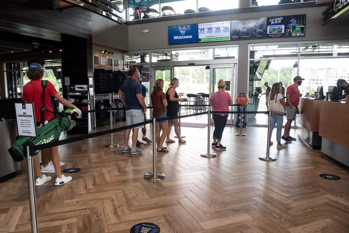 Patrons stand in line in the lobby of TopGolf, Monday August 3, 2020. Among their precautions are stickers in the lobby to encourage social distancing measures.