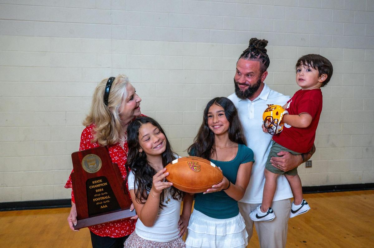 West Charlotte football coach Sam Greiner and his family pose for a portrait at Charlotte’s Independence High School.