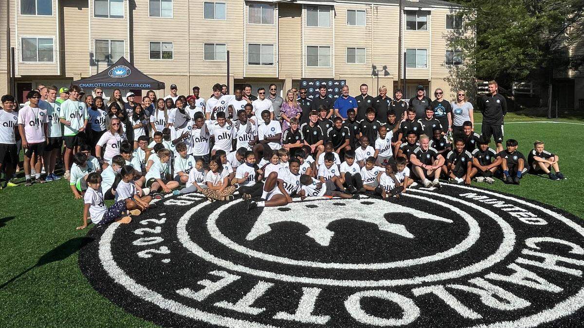 Charlotte FC development academy team poses at a new turf mini pitch installed at The Apartments at Sailboat Bay in East Charlotte as part of the team’s “Pitches for Progress” initiative earlier this year. Fans hope that the simple white and black kits the academy team wears won’t be what the MLS team dons in their inaugural 2022 season.