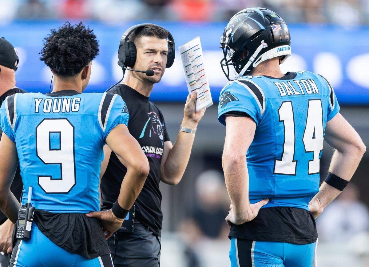 Carolina Panthers coach Dave Canales, center, speaks to Carolina Panthers quarterbacks Andy Dalton (14) and Bryce Young (9) at Bank of America Stadium in Charlotte on Sunday, October 13, 2024.