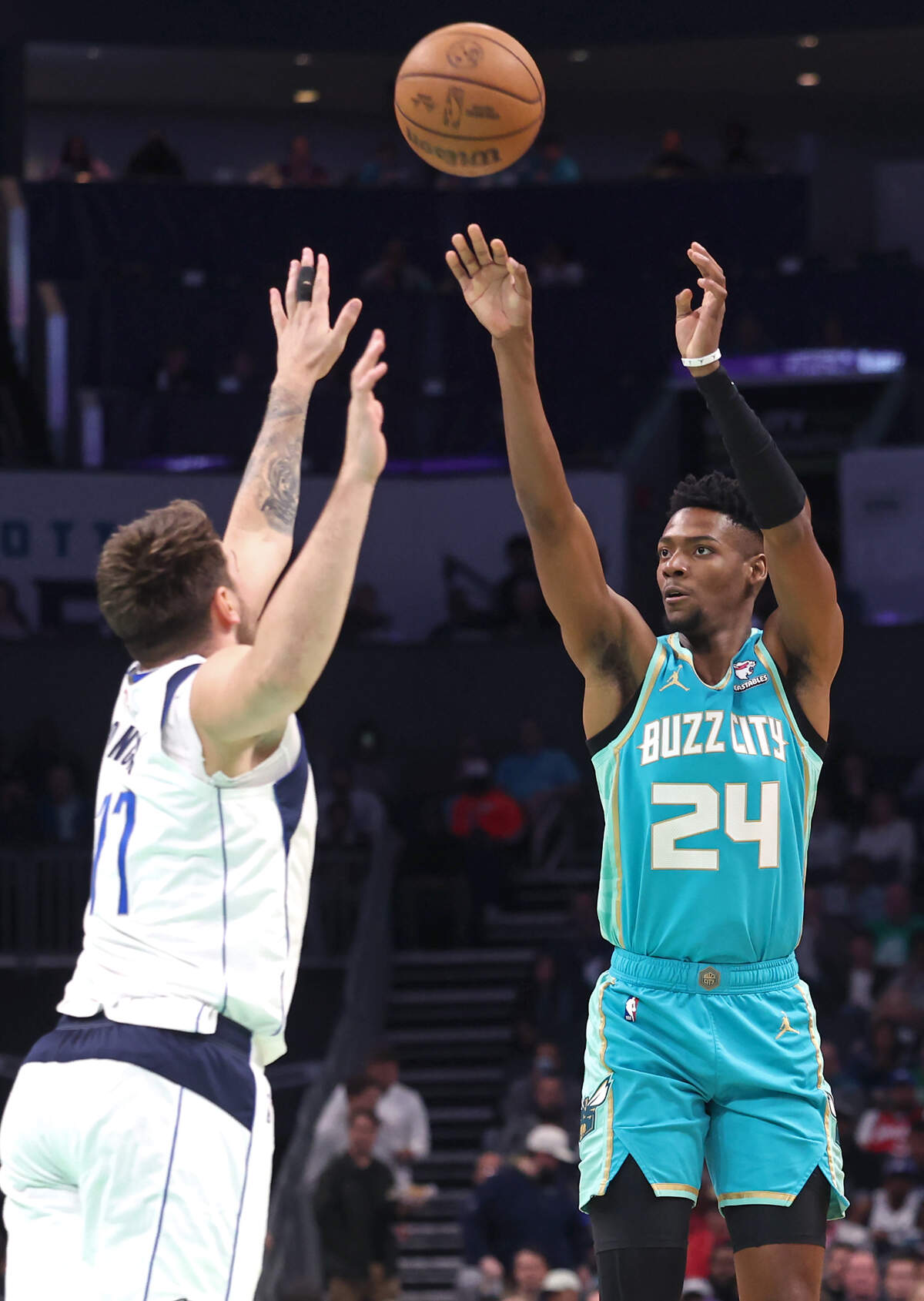 Charlotte Hornets forward/guard Brandon Miller, right, releases a jump shot over Dallas Mavericks guard Luka Doncic, left, during first-half action at Spectrum Center in Charlotte, NC on Tuesday, April 9, 2024. The Mavericks defeated the Hornets 130-104.