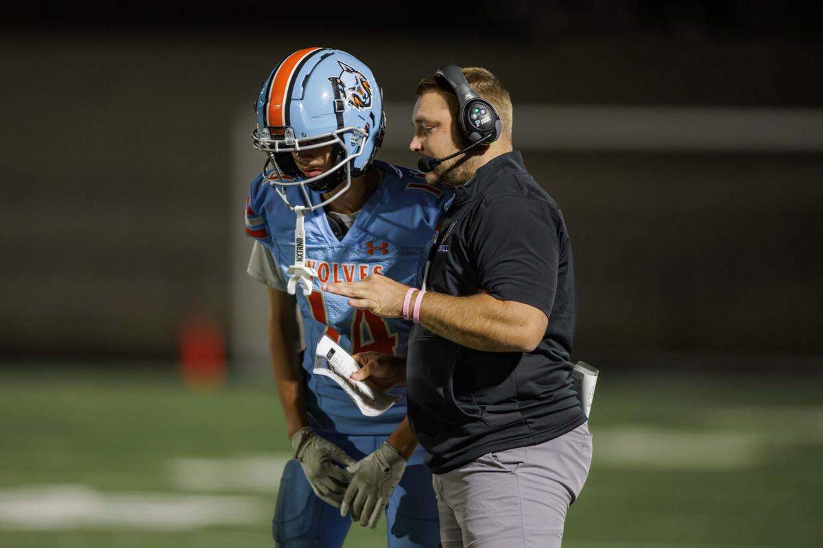 Ballantyne Ridge head football coach Chris Redding (right) calls in the play to wide receiver Devin Delfino (14). Ballantyne Ridge Wolves would host the Berry Cardinals on a Thursday night game October 10, 2024.