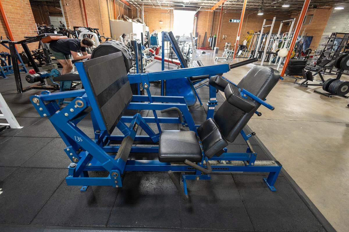 A heavy-duty, blue MedX Avenger leg press machine with black padded seating, centered on a black rubber mat.