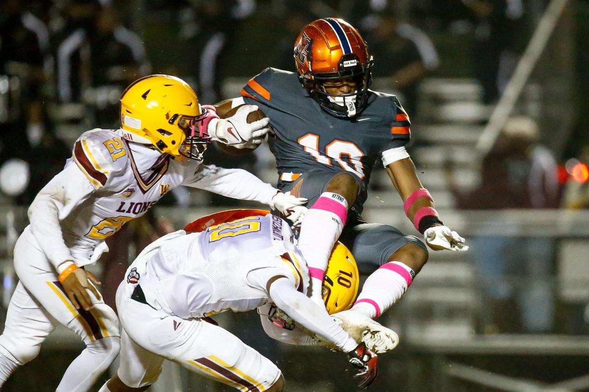 Chambers senior Braylon Vinson (10, top) hurdles over West Chambers junior Demetrius Rivers (10, bottom) at Julian L. Chambers High School on October 20, 2023.