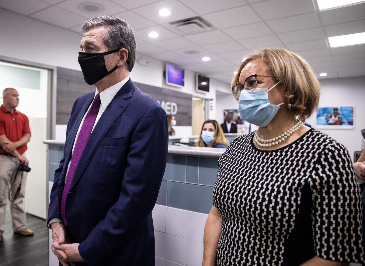 Gov. Roy Cooper, left, greets employees with Mayor Vi Lyles at a StarMed clinic in Charlotte, N.C., on Thursday, June 3, 2021.