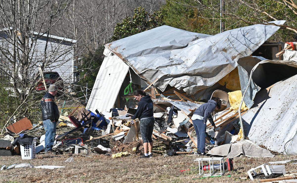 Richard Pack, left, Brandy Bradley and Melanie Pack attempt to salvage items from a mobile home along Cindi Lane in Claremont, NC on Wednesday, January 10, 2024. The Pack’s cousin Dustin Weaver had been living at the residence when he was killed on Tuesday, January 9th.