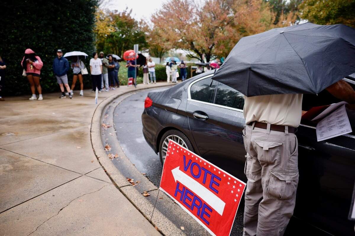 A poll worker brought a ballot to a voter in a car at Charlotte Mecklenburg Library at University City on Tuesday. About 200 voters were in line waiting to vote, and the estimated wait time was around an hour.