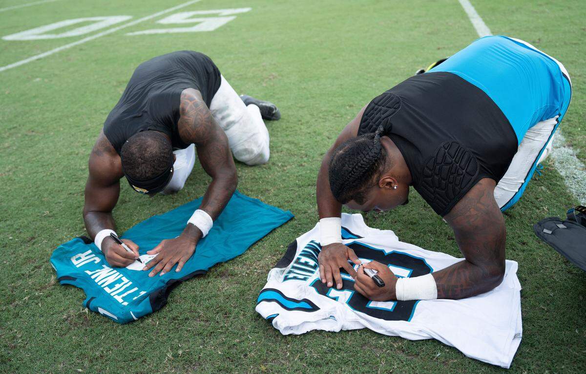 Jacksonville Jaguars running back Travis Etienne Jr. (1), left wrote a message to his brother Carolina Panthers running back Trevor Etienne (23) before exchanging their jerseys after the game between the Carolina Panthers at Jacksonville Jaguars at EverBank Stadium Sunday September 7, 2025. Jaguars defeated the Panthers 26-10. [Doug Engle/Florida Times-Union]